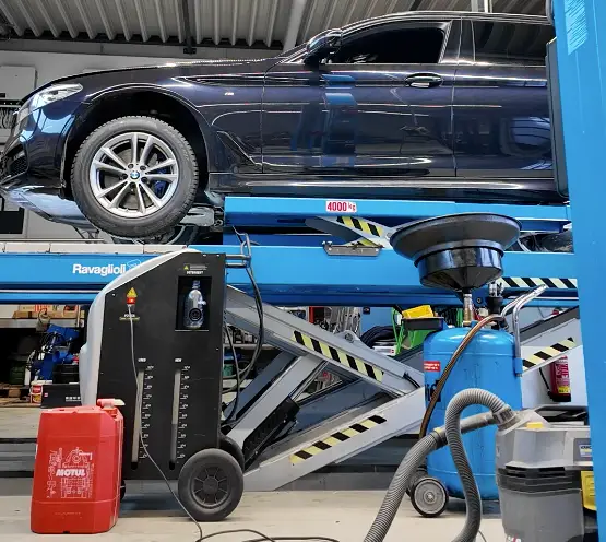 Start 5 Dunkelblauer 5er Bmw auf einer hellblauen Hebebühne in einer Kfz-Werkstatt